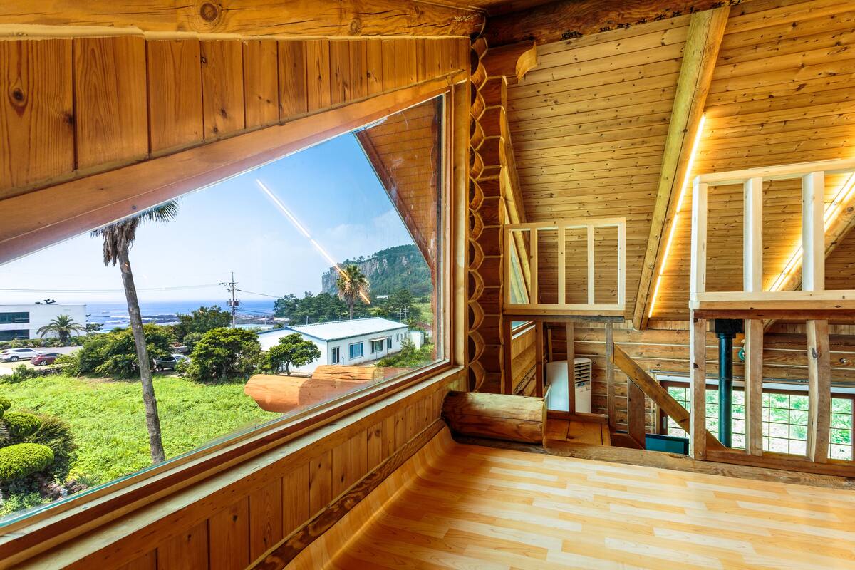 A wooden interior with a large window overlooking a lush landscape.