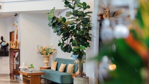 A living room with a sofa, a coffee table, and a potted plant. - Sandy Spring Hotel (Pattaya)