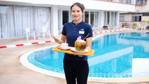 A person holding a tray with a drink and a coconut. - Sandy Spring Hotel (Pattaya)