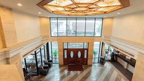A spacious lobby with a high ceiling, large windows, and a reception desk. - Sandy Spring Hotel (Pattaya)