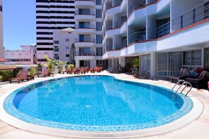 Een buitenzwembad, parasols bij het zwembad en ligstoelen