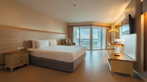 A modern hotel room with a large bed, a desk, and a balcony with a view. - Sandy Spring Hotel (Pattaya)