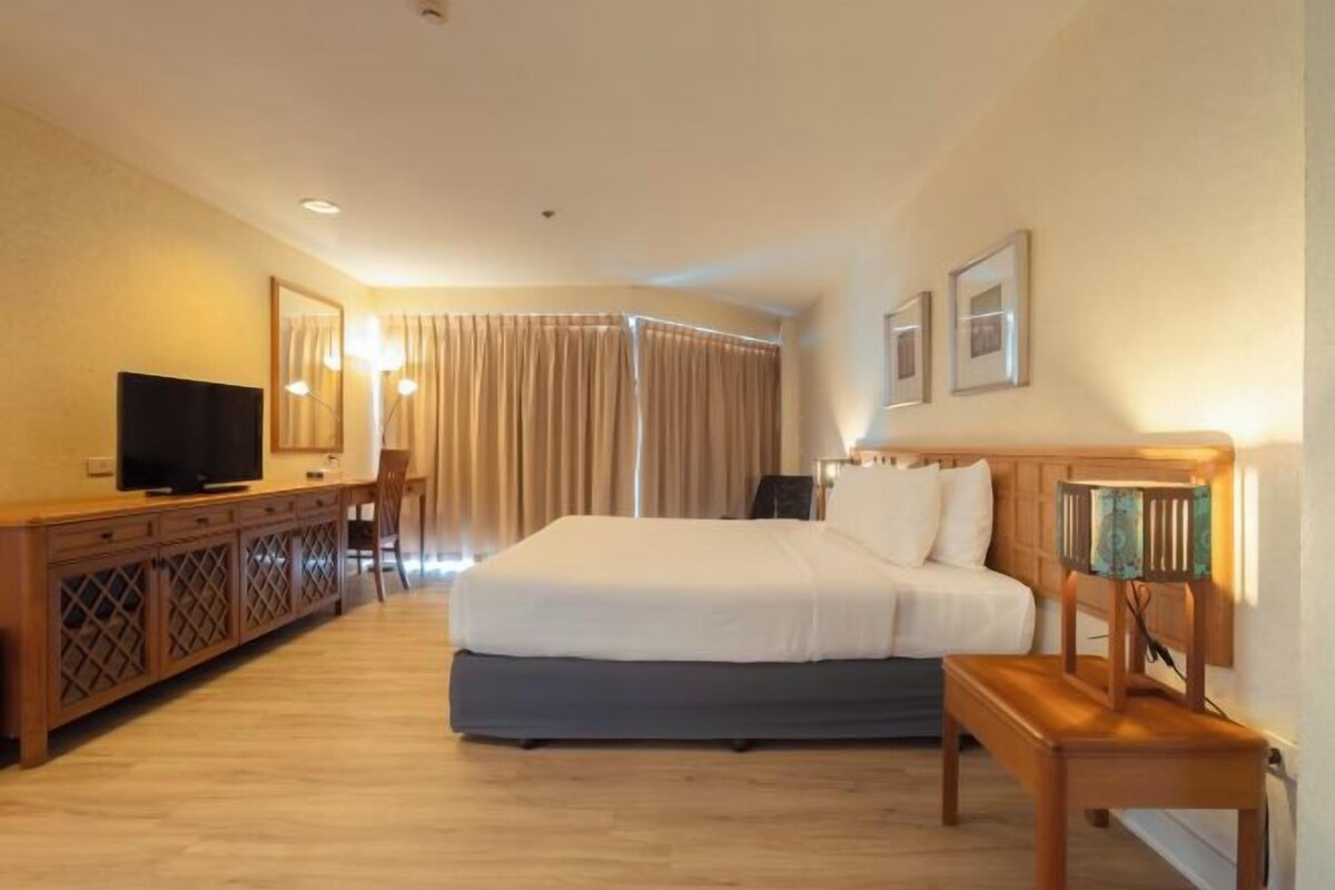 A hotel room with a bed, a TV, a desk, and a chair.
