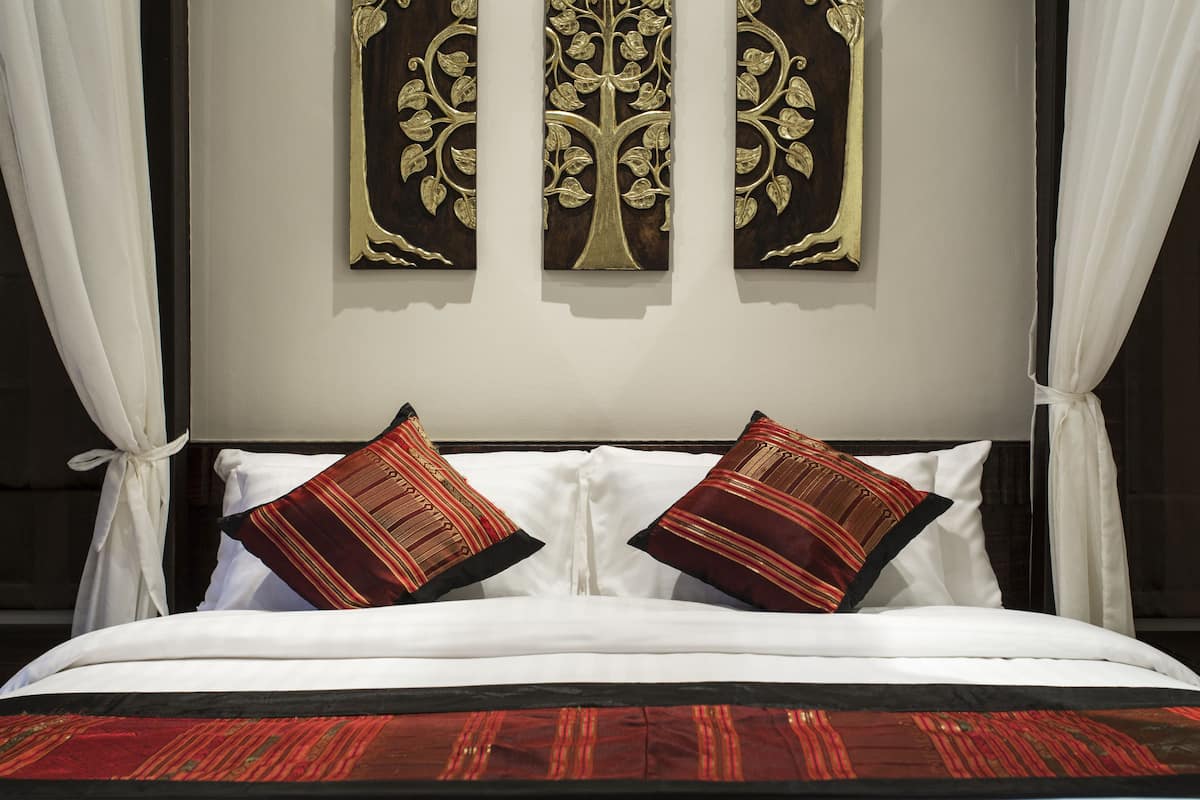 A bed with white linens, two red and black striped pillows, and a red and black striped bedspread.