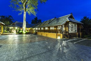 A traditional building with a tiled roof and wooden structure, surrounded by a paved area with a tree and lights. - Getaway Chiang Mai Resort & Spa (Doi Saket)