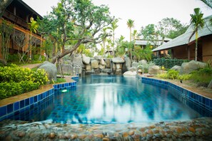 A serene indoor pool with a natural rock and tile design, surrounded by lush greenery and traditional architecture. - Getaway Chiang Mai Resort & Spa (Doi Saket)