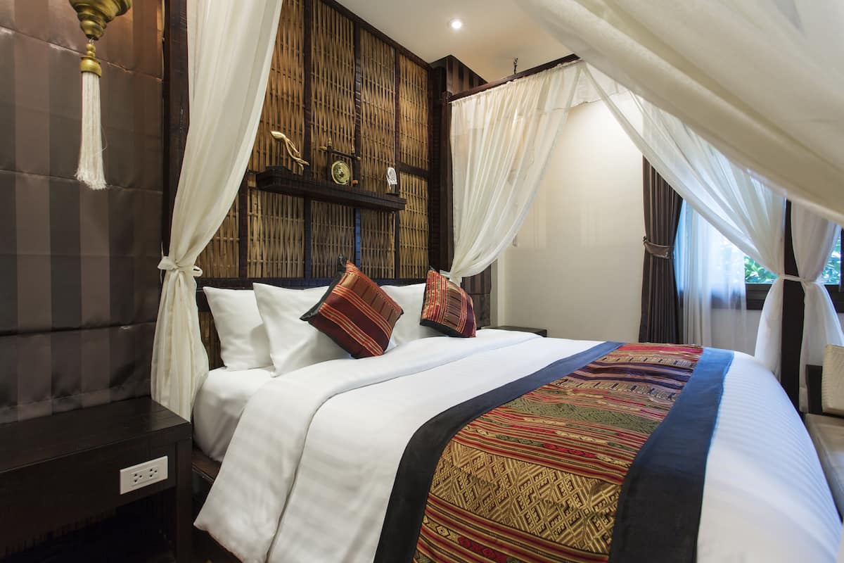 A neatly made bed with a patterned bedspread, white pillows, and a canopy.
