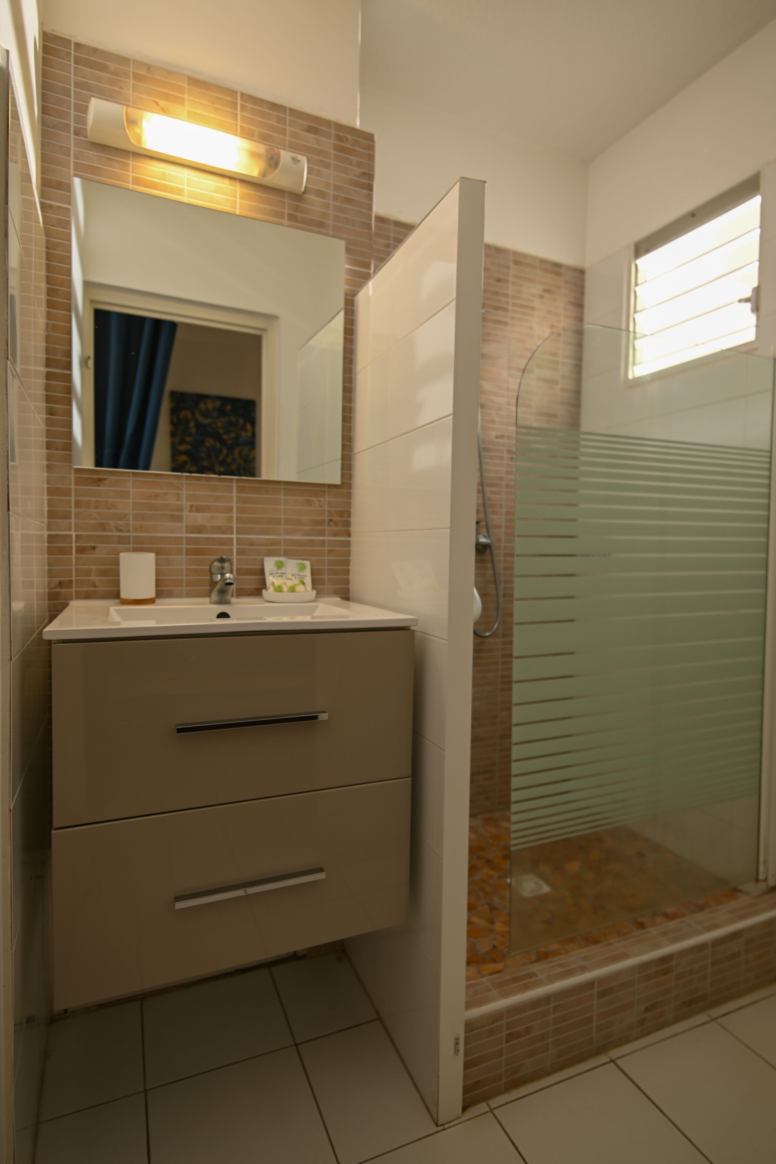 A bathroom with a sink, mirror, and shower.