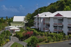 Un resort con edificios de varios pisos, balcones y abundante vegetación.
