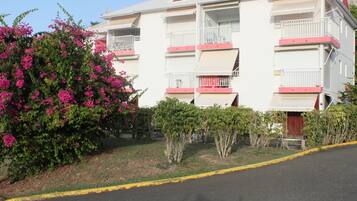 Un edificio de varios pisos con balcones, techo rojo y bordillo amarillo.