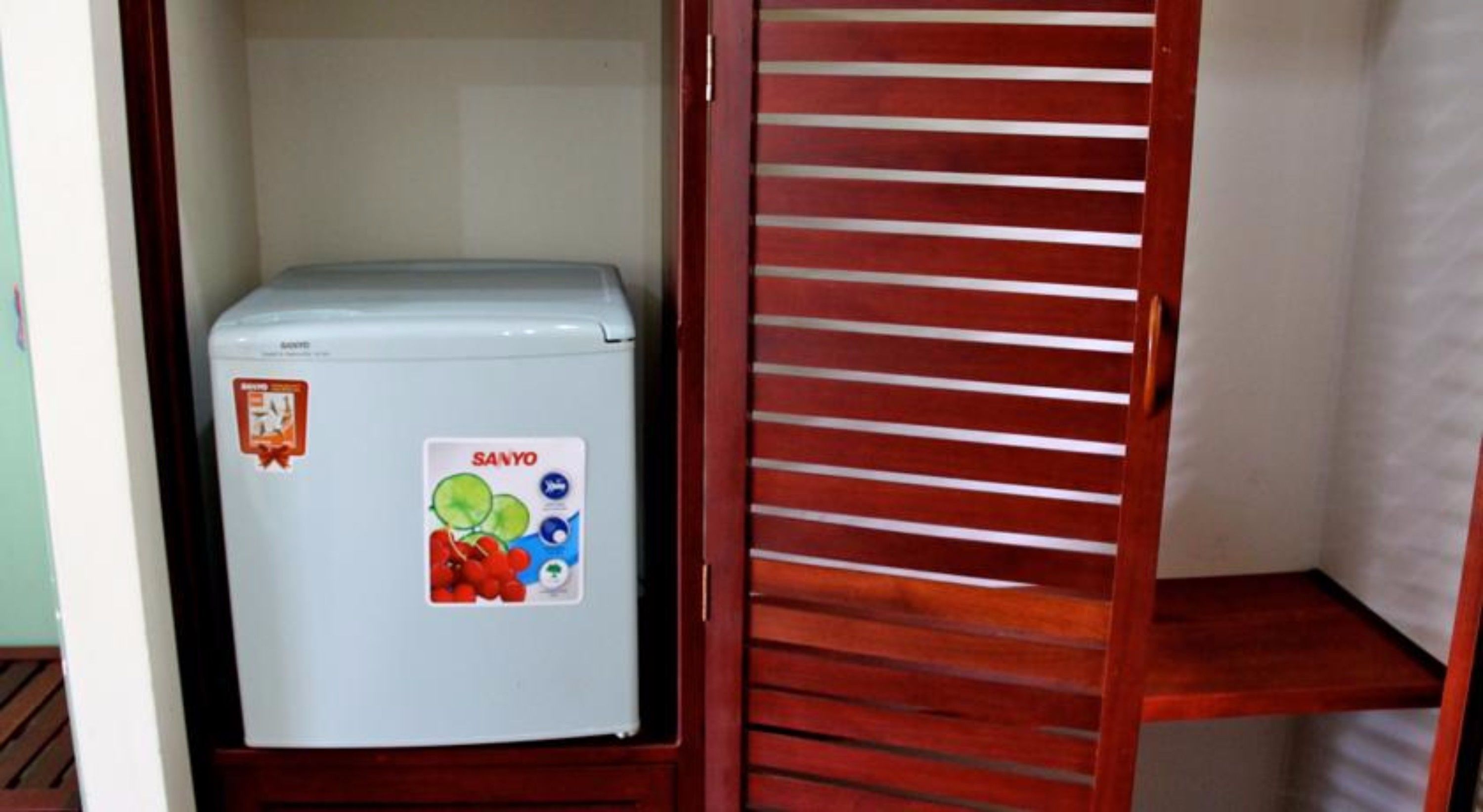 Ein kompakter Kühlschrank mit Aufkleber, platziert in einem Raum mit einer Holzlattenwand.