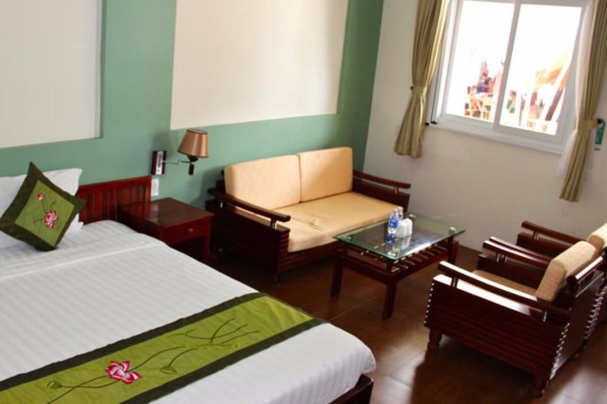 A hotel room with a bed, a sofa, a small table, and a chair.