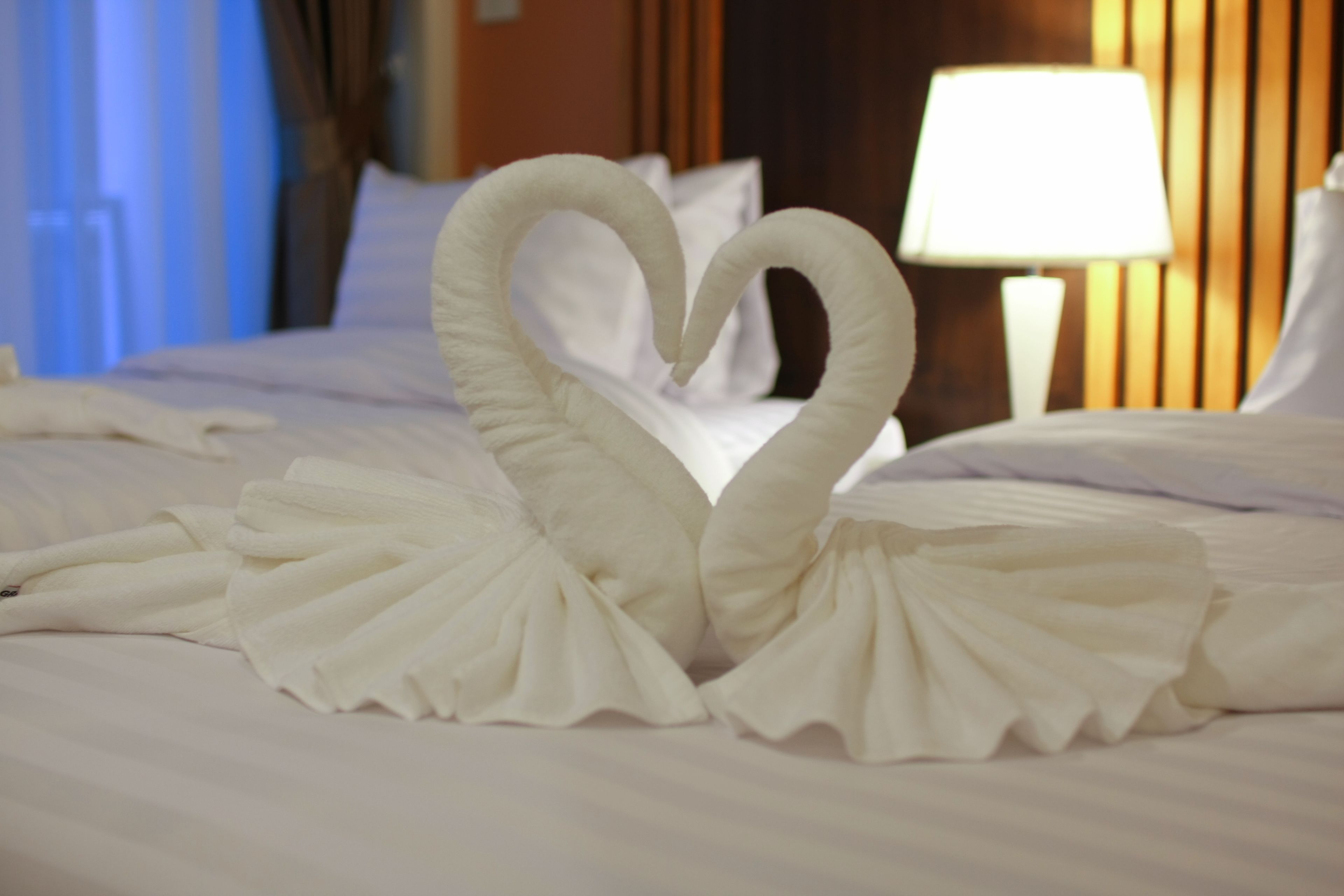 A bed with a heart-shaped towel arrangement.