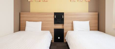 Habitación de hotel con dos camas, cabecera de madera, un reloj de pared y un estante pequeño con una botella y un control remoto.