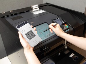 A person using a smartphone and a pen to interact with a printer, possibly for printing a receipt. - Comfort Hotel Wakayama (Wakayama)