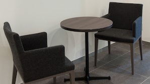A room with a flat-screen TV mounted on the wall, two grey upholstered chairs, and a round table. - Comfort Hotel Wakayama (Wakayama)