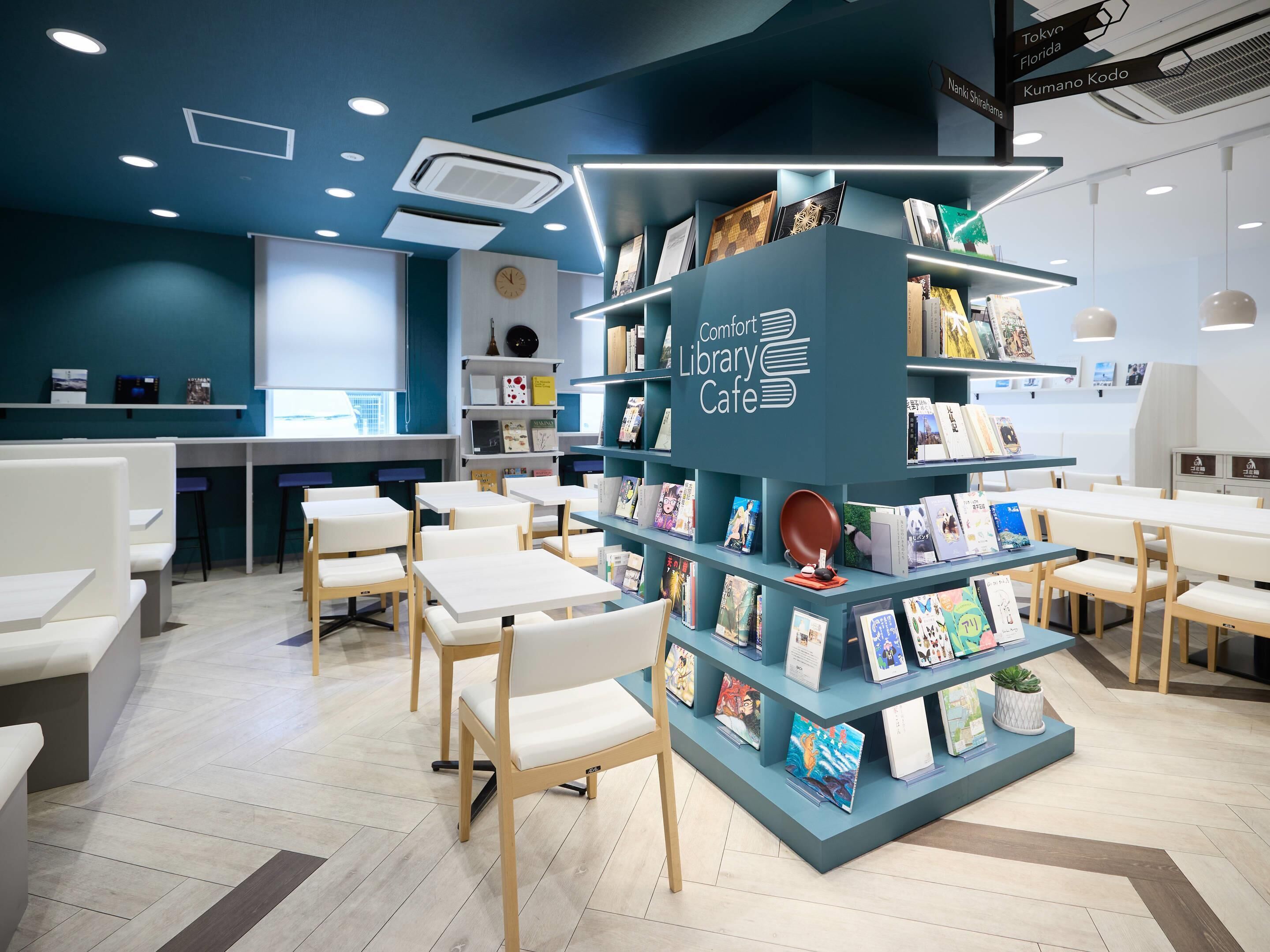 Ett café i ett bibliotek med bokhyllor, sittplatser och en klocka på väggen.