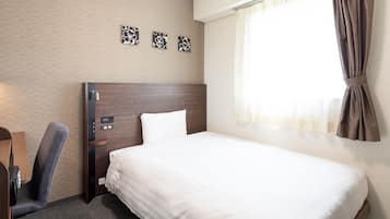 Habitación de hotel con cama, escritorio, silla, mesita de noche y ventana con cortinas.