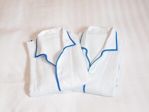 Batas blancas bien dobladas con detalles azules sobre una cama.