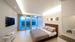Een moderne slaapkamer met een groot bed, een televisie en een schuifdeur naar een balkon.
