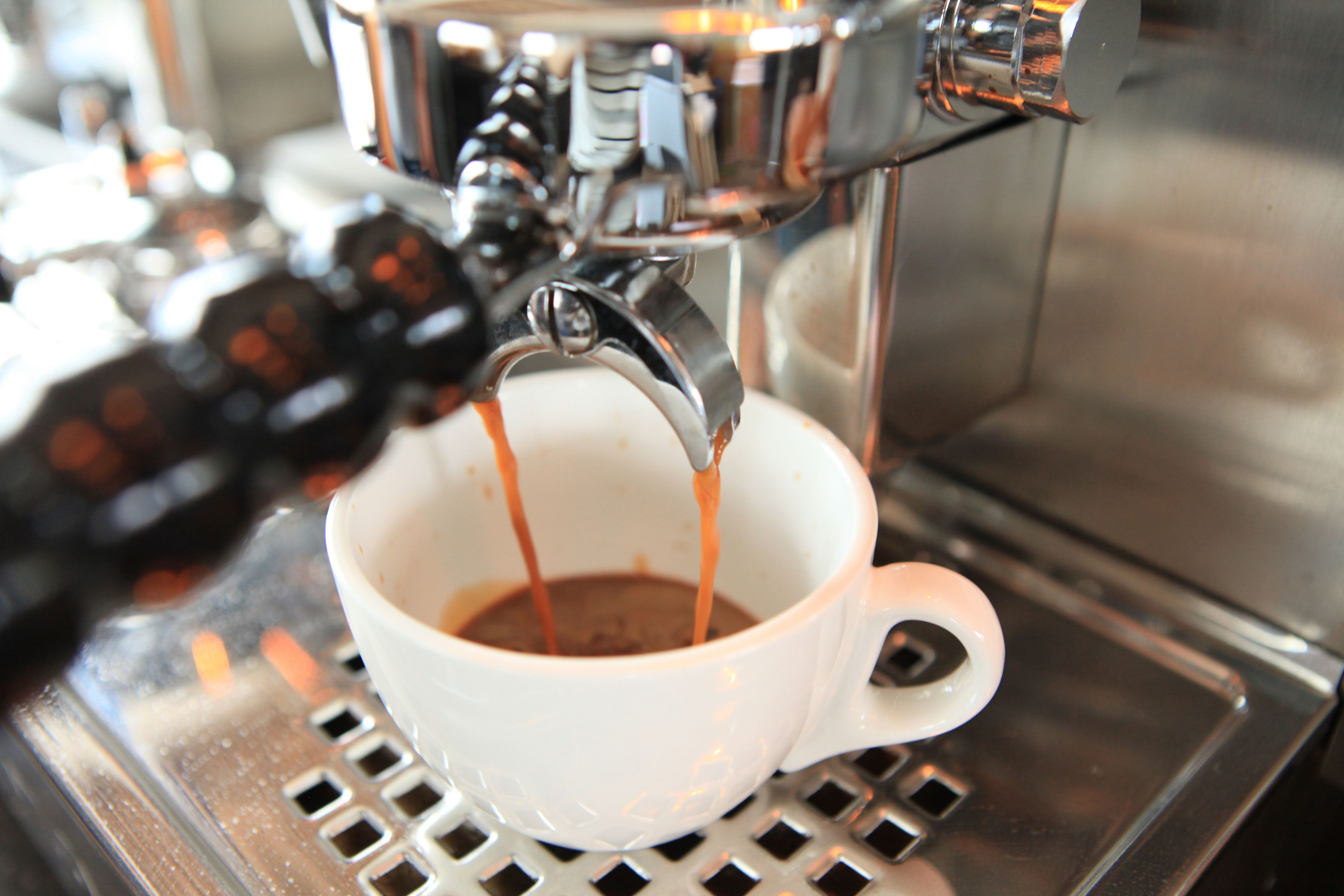 Eine Kaffeemaschine gibt Espresso in eine weiße Tasse ab.