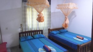 A room with two beds, each with blue bedding and a mosquito net hanging above. - Pradeepa Guest House (Polonnaruwa)