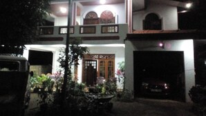 A two-story house with a balcony, a garage, and a well-lit entrance. - Pradeepa Guest House (Polonnaruwa)