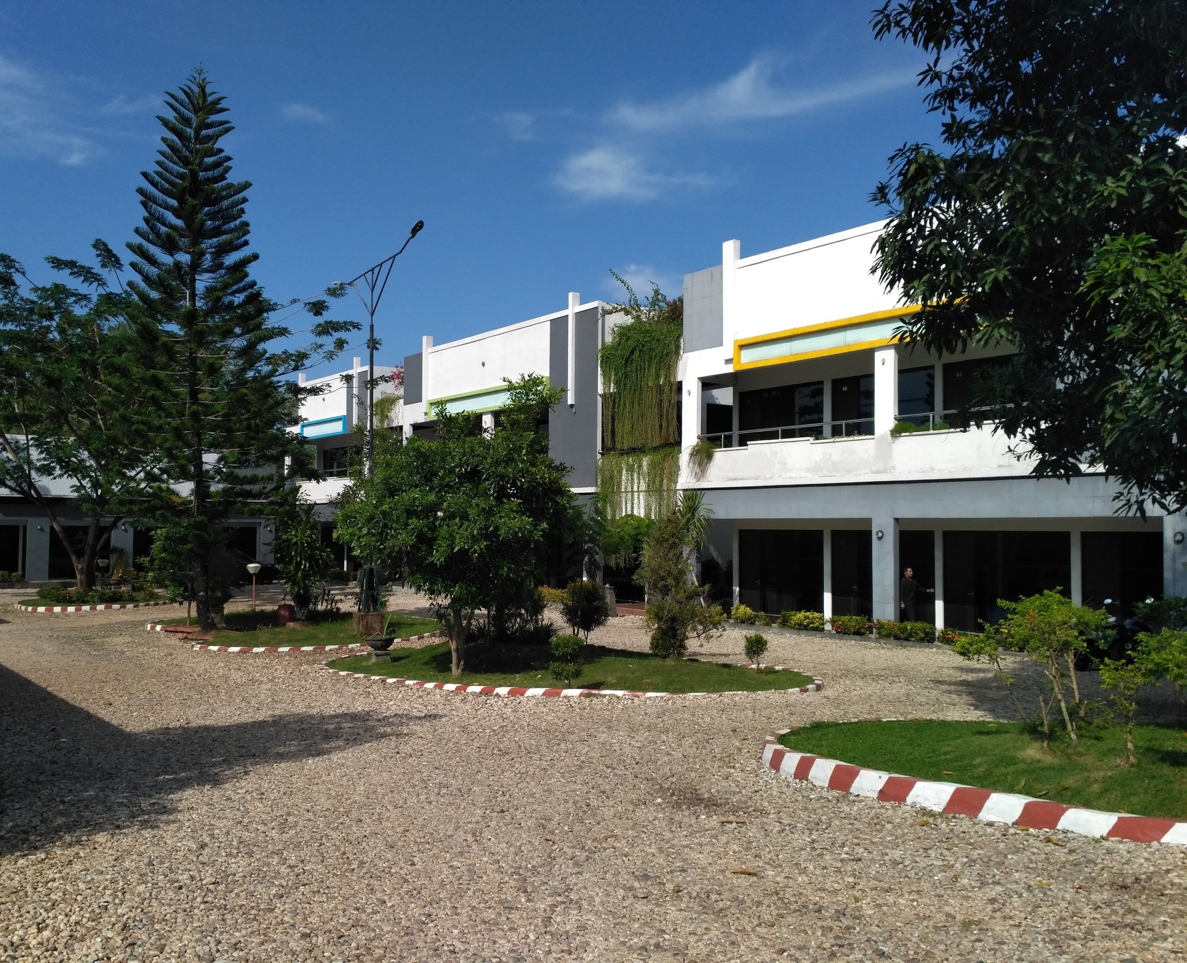 Un edificio moderno con fachada blanca, múltiples ventanales y techo verde.