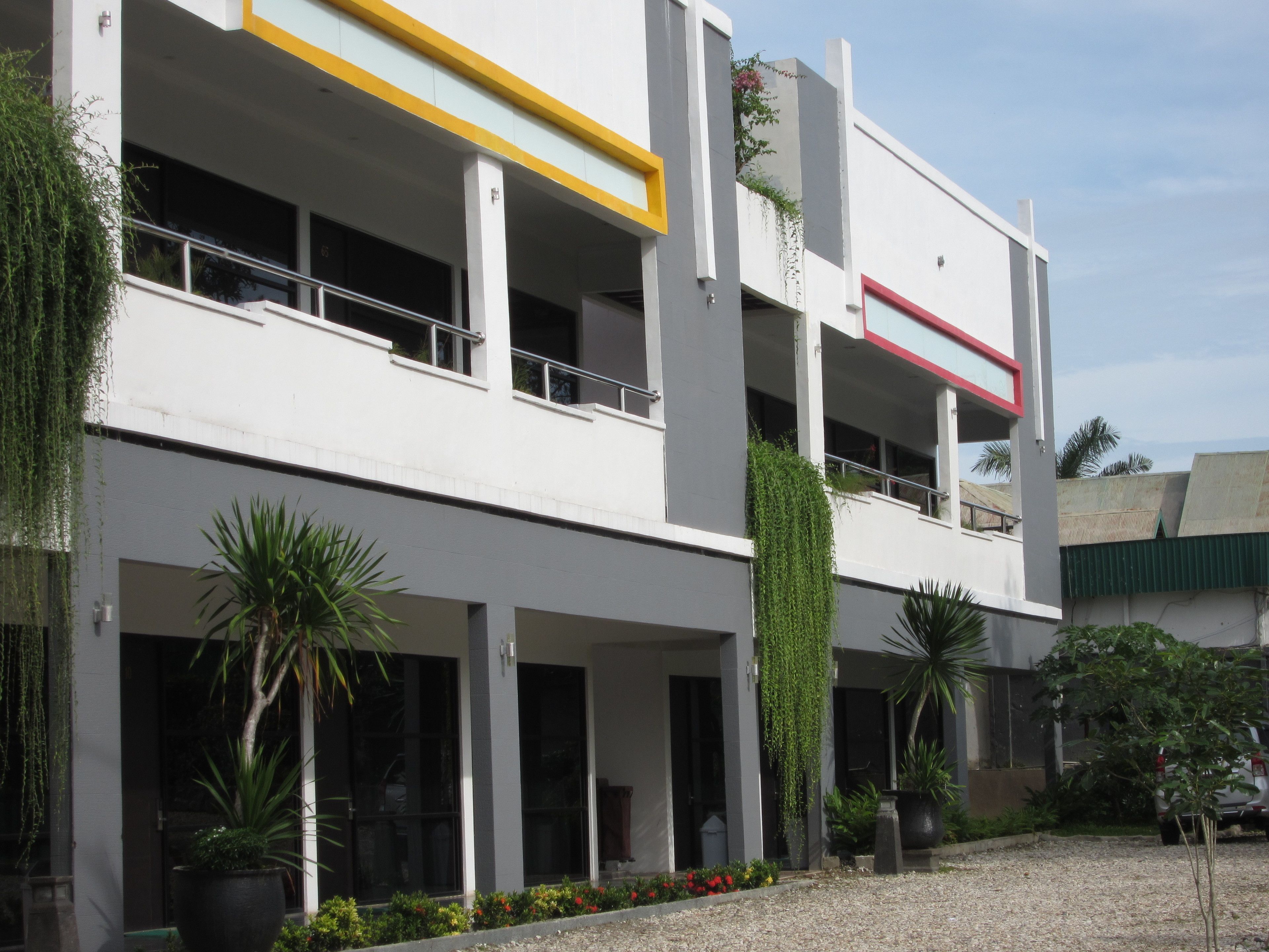 A modern building with multiple balconies, large windows, and potted plants.