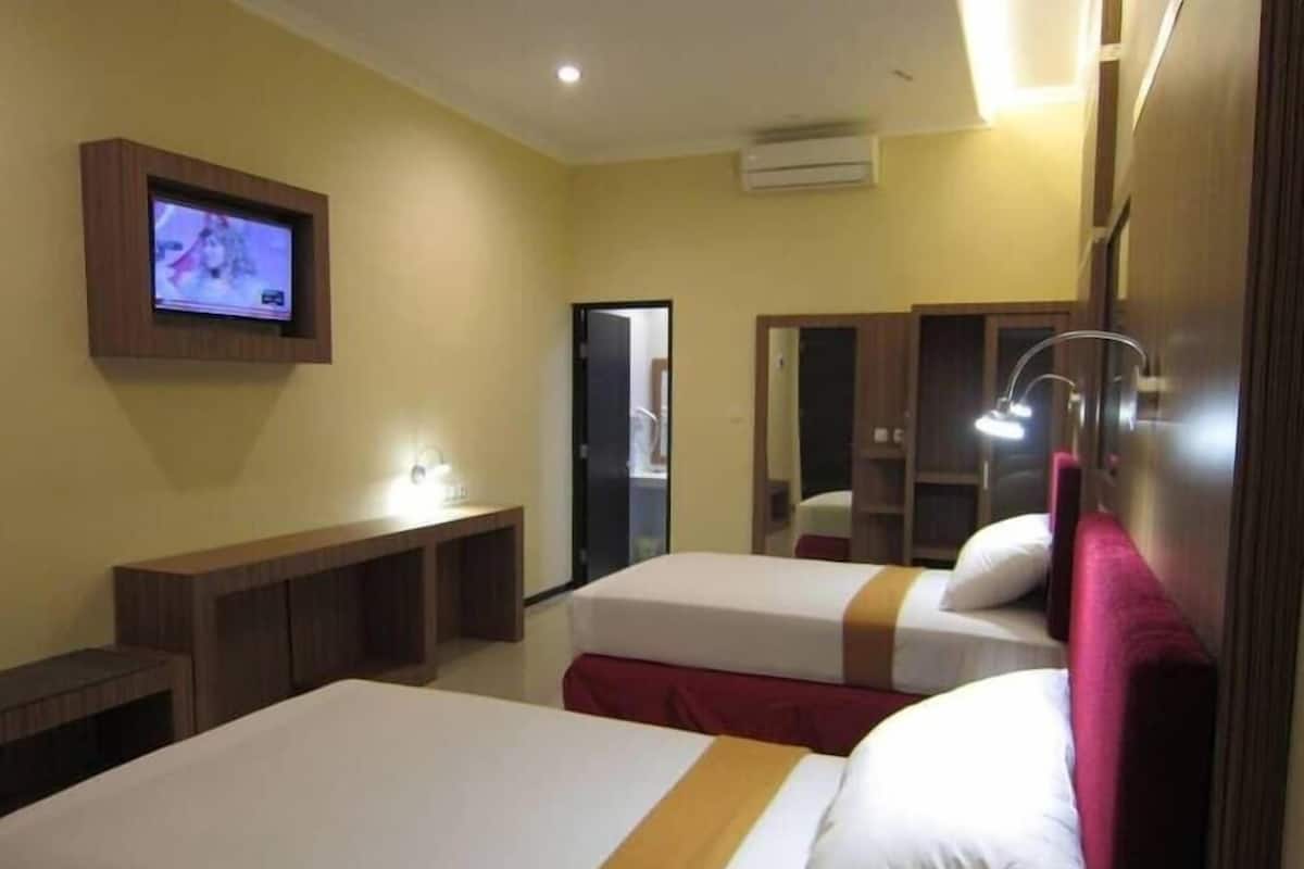 A hotel room with two beds, a TV, a desk, and a wardrobe.