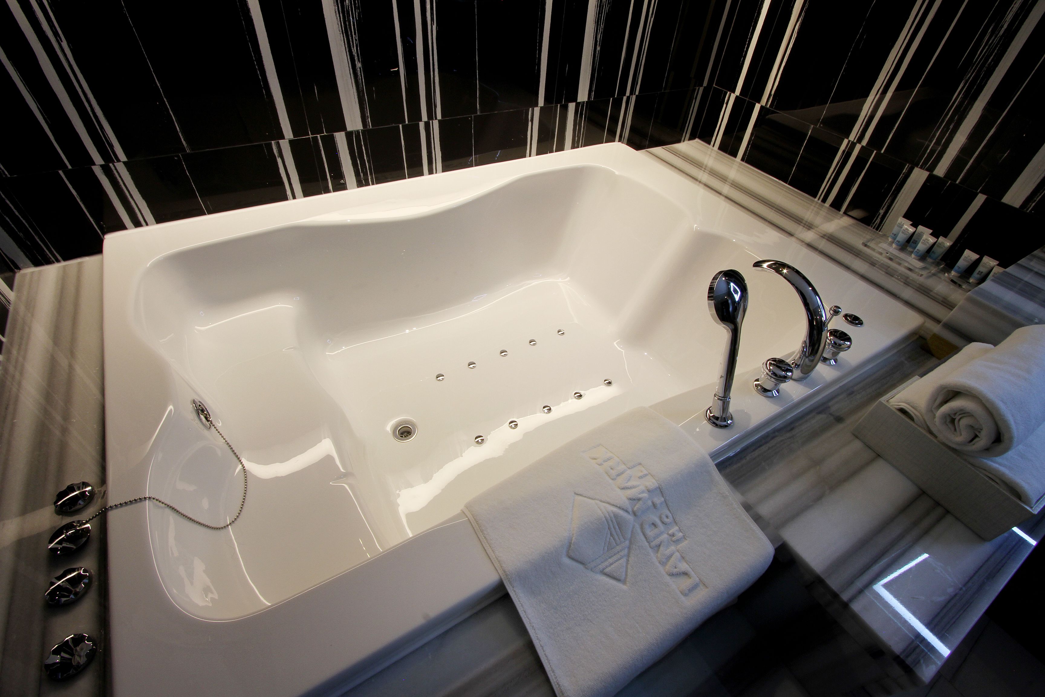 Une salle de bain moderne dotée d’une grande baignoire, d’un espace douche et d’un porte-serviettes.