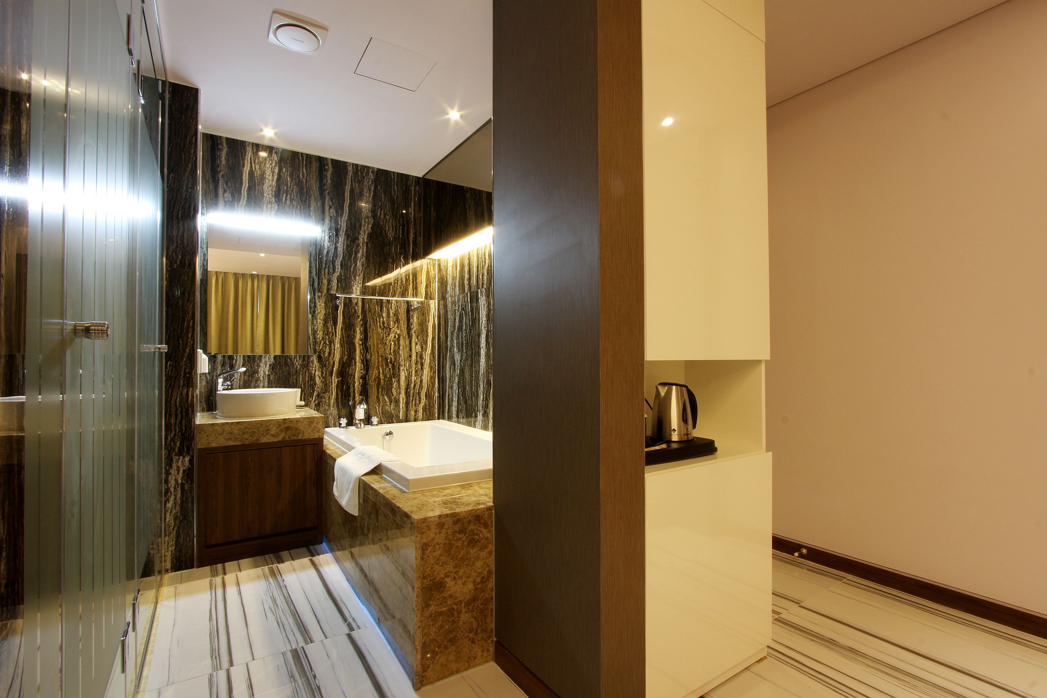 Un baño moderno con tocador de mármol, bañera y un espejo grande.