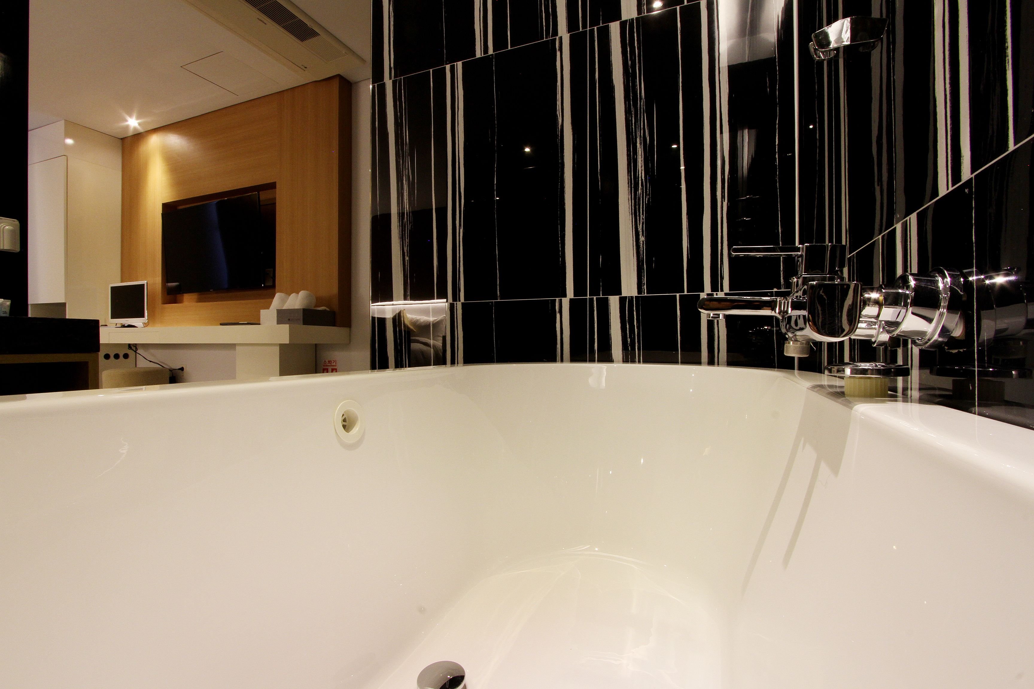 A modern bathroom with a large bathtub, a wooden vanity, and a large mirror.