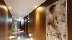 A modern hotel hallway with wooden paneling and a large abstract painting on the wall.