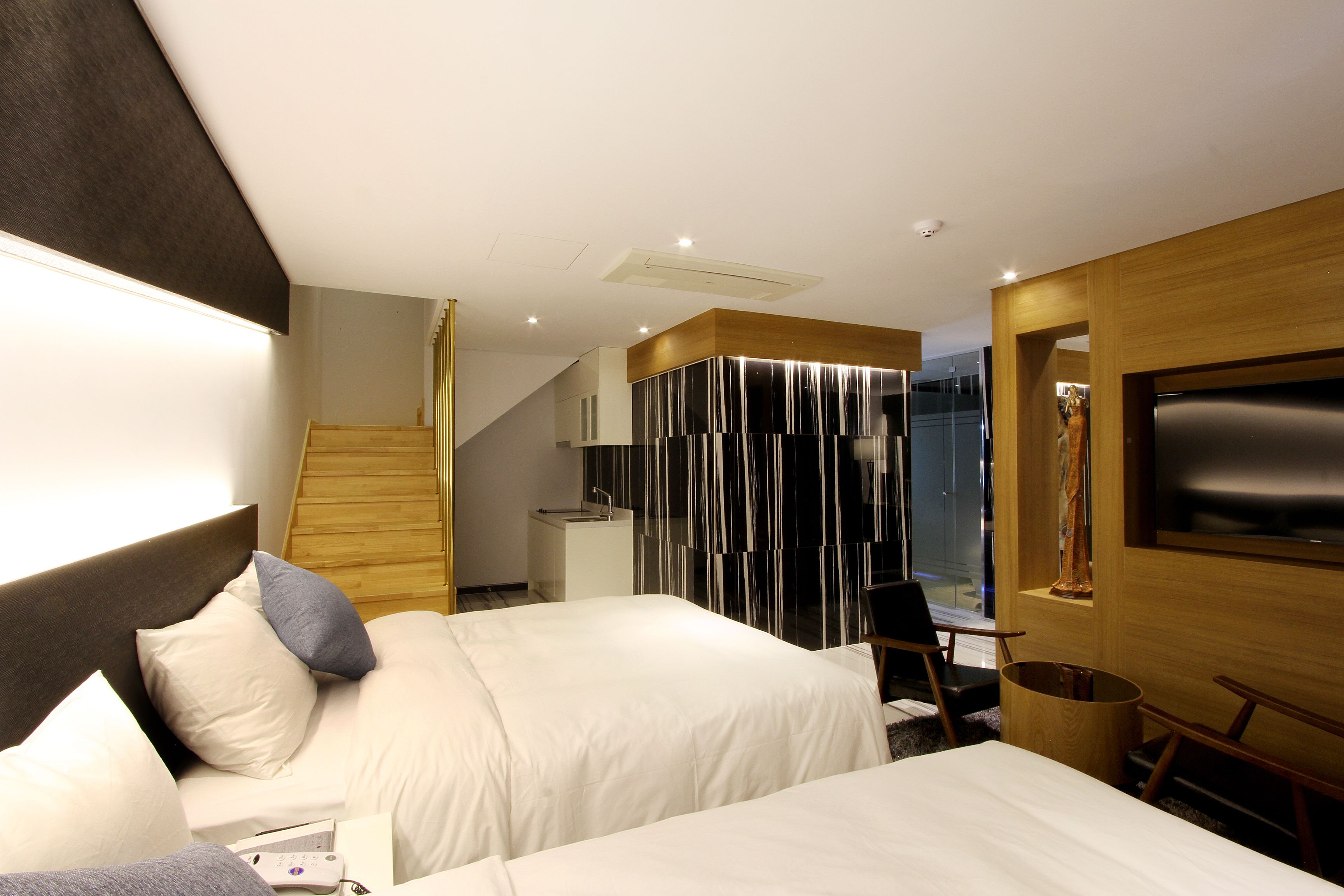 Une chambre d’hôtel moderne équipée de deux lits, d’une télévision, d’un bureau et d’une salle de bain.
