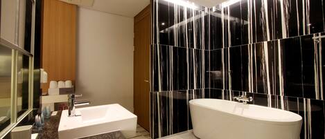 Un baño moderno con una bañera independiente, un tocador con lavabo y un espejo.