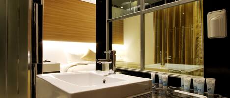 A modern bathroom with a large sink, a mirror, and spa service products on the counter.