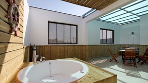 A modern bathroom with a freestanding bathtub, wooden paneling, and large windows allowing natural light.