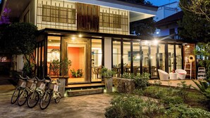 Un edificio moderno con fachada de vidrio, zona de estar exterior y bicicletas estacionadas afuera.