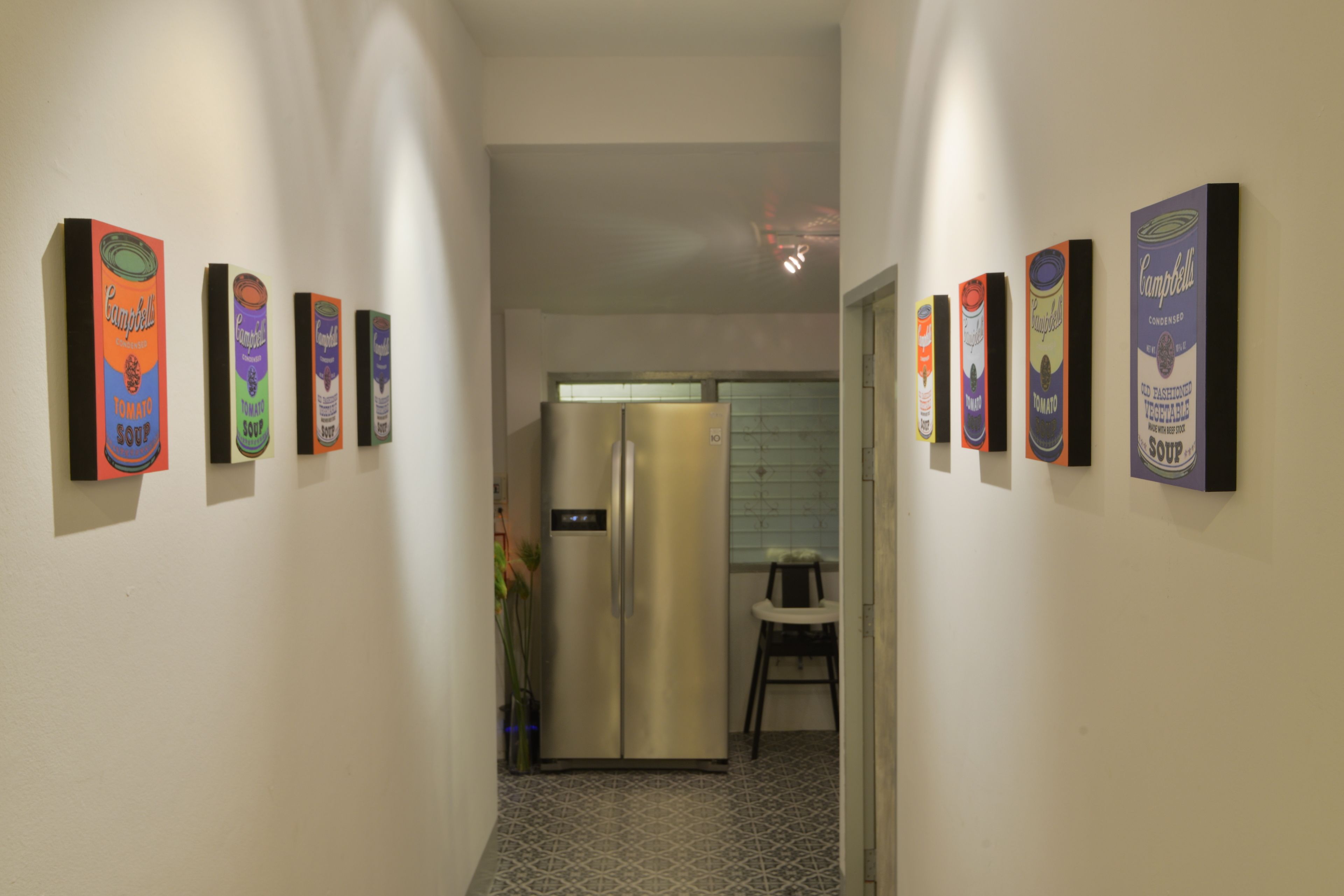 A narrow hallway with a refrigerator and a chair in the background.