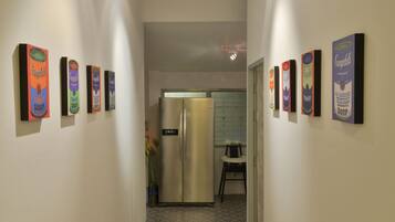 A narrow hallway with a refrigerator and a chair in the background.