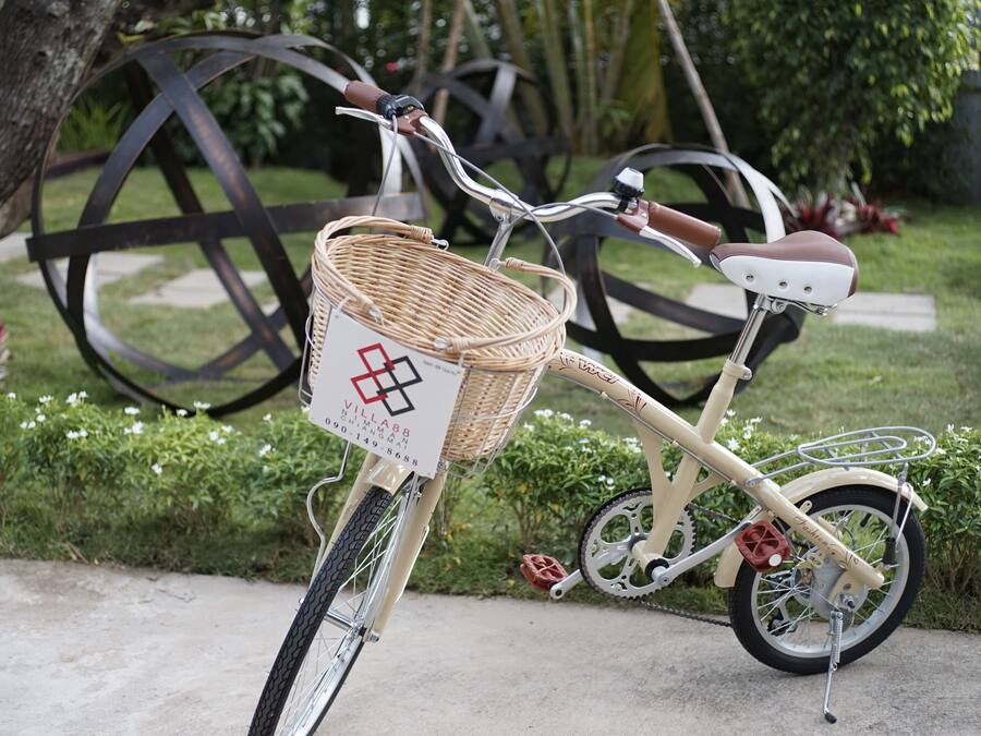 A vintage bicycle with a wicker basket and a seat with a cushion.