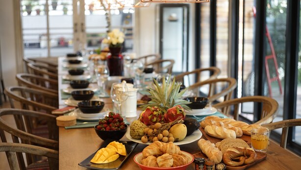 Una mesa de desayuno con frutas, bollería y bebidas.