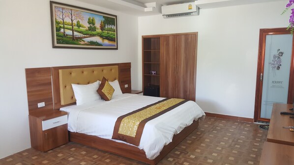 Une chambre bien rangée, avec un lit, une tête de lit en bois, des tables de chevet, une armoire et un tableau accroché au mur.