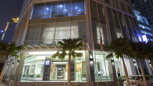 Un hotel moderno con fachada de vidrio, varios pisos y una entrada destacada.