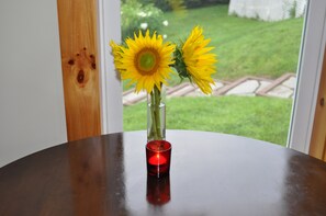 Una mesa con un jarrón de girasoles y una vela encendida.