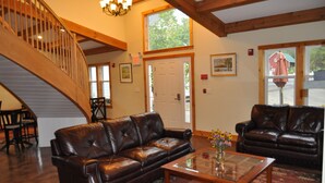 Un amplio salón con dos sofás de cuero, una mesa de centro de madera y una escalera con barandillas de madera.