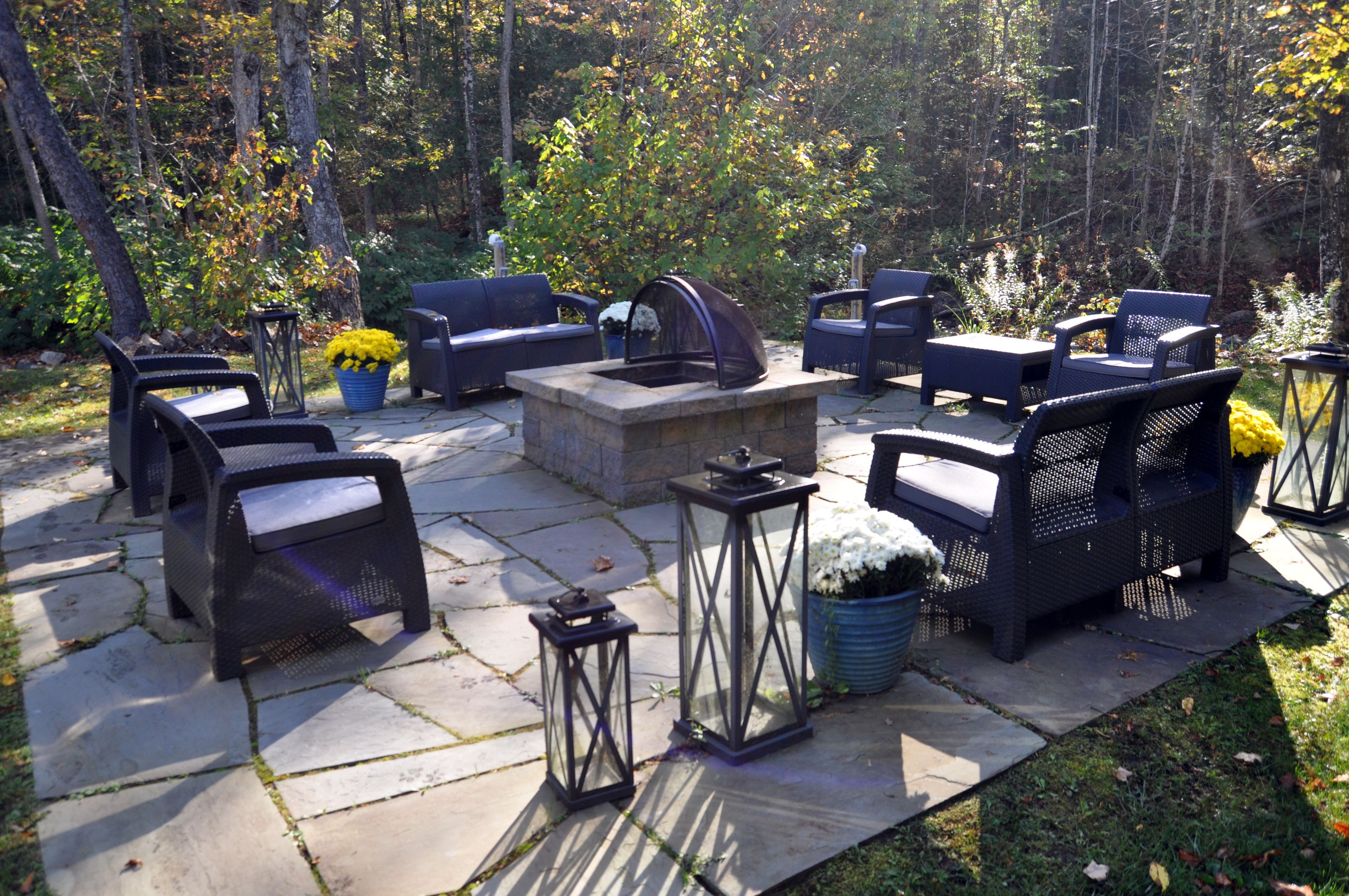 An outdoor patio with stone flooring, black wicker furniture, and lanterns.