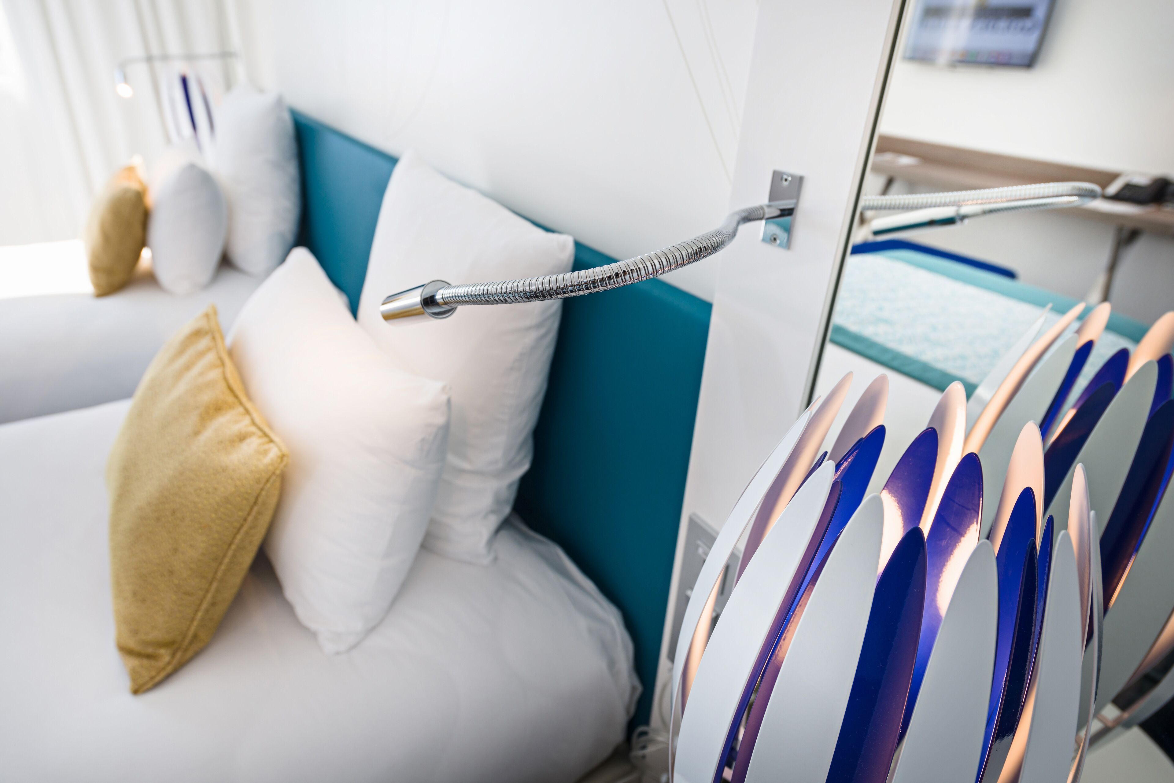 A modern hotel room with a bed, pillows, and a metal railing.