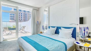 Une chambre d’hôtel avec un grand lit, un balcon avec des chaises et une vue sur un immeuble.